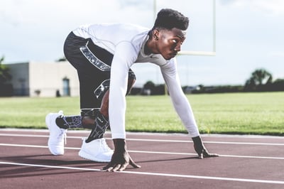 A runner prepares to set off from the starting line on a field track